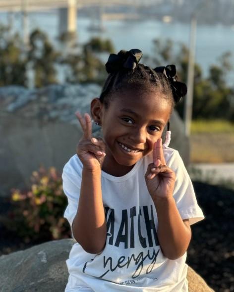 Nalani sitting on a rock, smiling and making peace signs